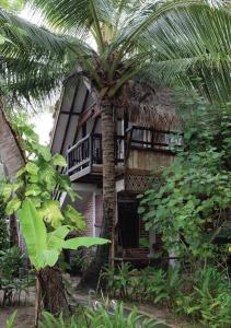 珍南海滩潘集潘集热带木屋别墅的棕榈树,位于带阳台的建筑前