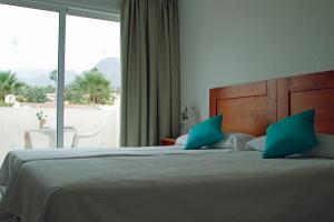 美洲海滩帕拉德洛二号酒店的一间卧室配有一张带蓝色枕头的床和一扇窗户。