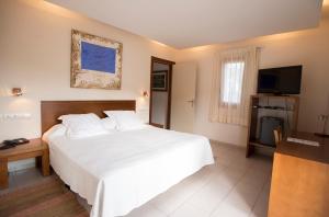 莱斯卡瑟斯-达尔卡纳Hotel Cal Naudi的卧室配有一张白色大床和电视。