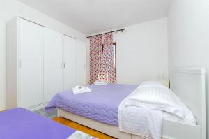 杜埃Apartment Jordan的白色卧室设有紫色的床和窗户