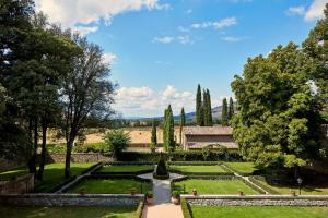 科尔托纳Villa di Piazzano - Small Luxury Hotels of the World的一座花园,花园内设有喷泉和树木,还有一座建筑