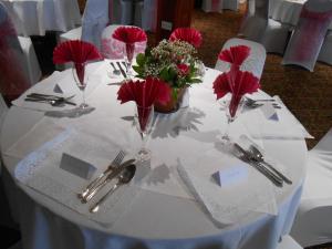 阿姆奇Dinorben Arms Hotel的一张白色的桌子,上面有红花和银器