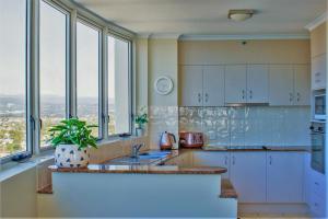 黄金海岸因迪格蓝色公寓式酒店的厨房配有白色橱柜、水槽和窗户。