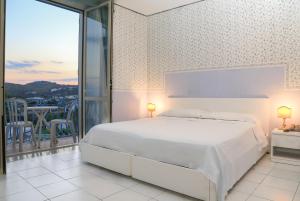 伊斯基亚罗蕾莱酒店的一间白色卧室,配有床和阳台