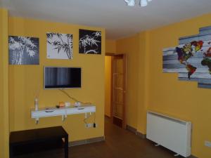 塞哥维亚El Balconcito de San Millan II的客房设有书桌和黄色墙壁上的电视