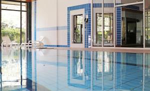 鲁瓦西昂法兰西千禧国际巴黎查尔斯戴高乐酒店的游泳池拥有蓝色和白色的瓷砖墙壁和窗户