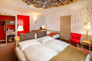 苏黎世瑞士之夜法斯宾德酒店的酒店客房,配有一张床和一张红色椅子