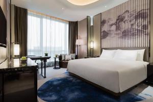 芜湖芜湖富力万达嘉华酒店的卧室配有一张白色大床和一张书桌