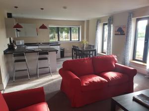 欧弗顿Oak & Hazel, Heath Row Barn的一间带红色沙发的客厅和一间厨房