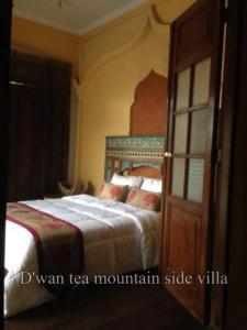 贾蒂卢维DWan Tea Mountain Side的一间卧室配有一张床和一扇木门