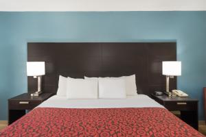 罗利罗利中城戴斯酒店的一间卧室配有一张带两盏灯的床和一部电话
