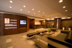 横滨新横滨大和鲁内酒店的酒店大堂设有沙发、桌子和电视。