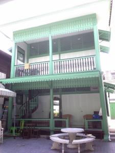 曼谷绿柚木房旅馆的一座带桌子和桌子的阳台的建筑