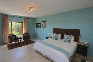 温特和克River Crossing Lodge的一间卧室配有一张床、两把椅子和一个窗户