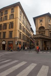 佛罗伦萨Le Tre Lune Suites的骑着自行车沿着建筑旁边的街道骑行的人