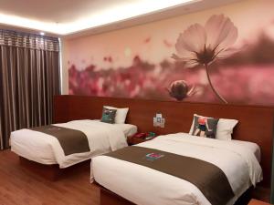 Kipekyüzi派酒店·伊宁华瑞国际商贸城店的墙上挂着花画的房间的两张床