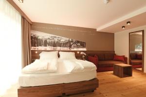 平佐洛Dolomeet Boutique Hotel的卧室配有一张白色的大床和一张沙发。