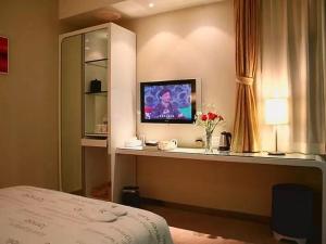 武汉天美乐饭店武汉武展店的酒店客房的一张桌子上配有电视,一张床铺