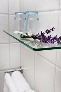 图什比萨尔斯特姆斯加登酒店的浴室里的玻璃架,上面有紫色的鲜花