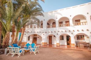 达哈布达哈卜潜水员酒店的白色的建筑,设有蓝色的椅子和棕榈树