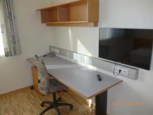 斯皮特安德劳Kolpinghaus Spittal的厨房配有书桌、电视和椅子