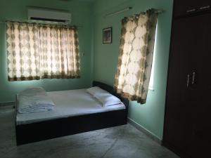 加尔各答Nalanda Tulip的一间小卧室,配有床和2个窗户