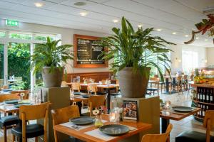 布雷达布雷达钟楼酒店及餐厅的一间设有桌椅和盆栽的餐厅