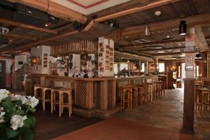 维林根多尔夫 - 阿尔姆酒店的餐厅内的酒吧设有木制天花板和木凳