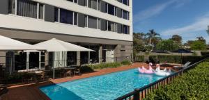 班克斯镇悉尼雷吉斯班克斯镇酒店的一座拥有粉红色天鹅的建筑前的游泳池