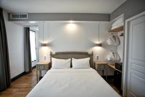 内拉克亨利四世酒店的一间卧室配有一张带白色床单的床和两张桌子