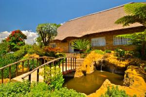 伯格维尔Hlalanathi Drakensberg Resort的一座桥,在一座房子前面的池塘上