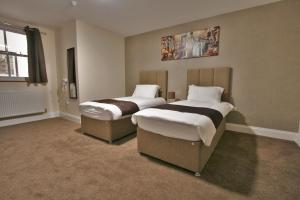 格洛斯特New County Hotel & Serviced Apartments by RoomsBooked的两张睡床,位于带喷雾器的房间