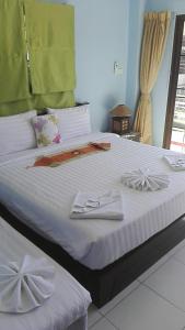 芭东海滩巴东拉皮卡拉宾馆的一间卧室配有一张带白色床单和弓的床铺