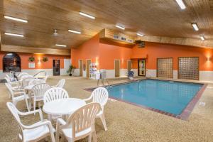 布鲁金斯布鲁金斯速8酒店的一个带白色桌椅的泳池间和游泳池