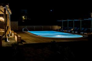 法纳里Anemoessa Luxury Villas的夜间游泳池,配有甲板和椅子