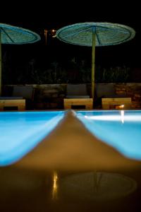 法纳里Anemoessa Luxury Villas的夜间游泳池,带遮阳伞