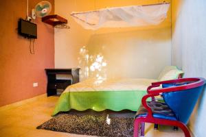 KitendeHotel Gorilla's Nest Entebbe的一间卧室配有一张床和一把椅子