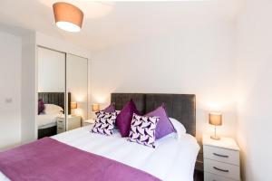 赫默尔亨普斯特德Abodebed Oval View Apartments的一间卧室配有一张带紫色枕头的大床