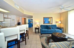 基韦斯特Sunrise Suites Big Kahuna Suite #202的一间带蓝色沙发的客厅和一间厨房