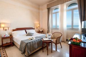 维亚雷焦Grand Hotel Royal的酒店客房设有床、桌子和窗户。