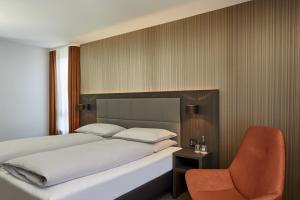 拜罗伊特拜罗伊特王宫H4酒店的一间卧室配有一张床和一把椅子