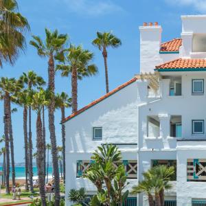 圣克莱门特圣克莱门特湾度假酒店的一座白色的建筑,在海洋前方种有棕榈树