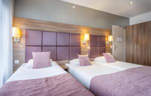 阿姆斯特丹维多利亚酒店的配有紫色床头板的酒店客房内的两张床