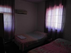 安塔利亚Sunrise Hotel的小房间设有两张床和粉红色窗帘
