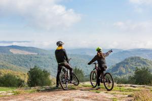 卡斯特利纳-因基安蒂卡珀文托别墅酒店的两人骑车在山丘上欣赏风景