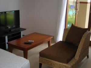 沙努尔Fruits Villa的客厅配有桌子、椅子和电视