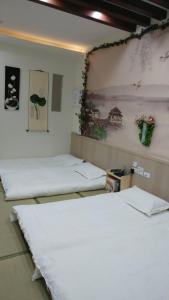 台南基石民宿 的一间设有三张床的客房,墙上挂着一幅画