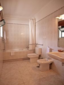 莫加多鲁Hotel Trindade Coelho的浴室配有卫生间、浴缸和水槽。
