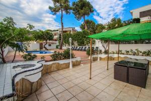 莫莱拉Pedro - two story holiday home villa in El Portet的一个带烧烤架和绿色遮阳伞的庭院