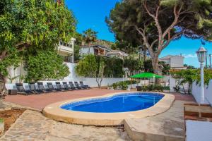 莫莱拉Pedro - two story holiday home villa in El Portet的庭院内的游泳池,带椅子和树木
